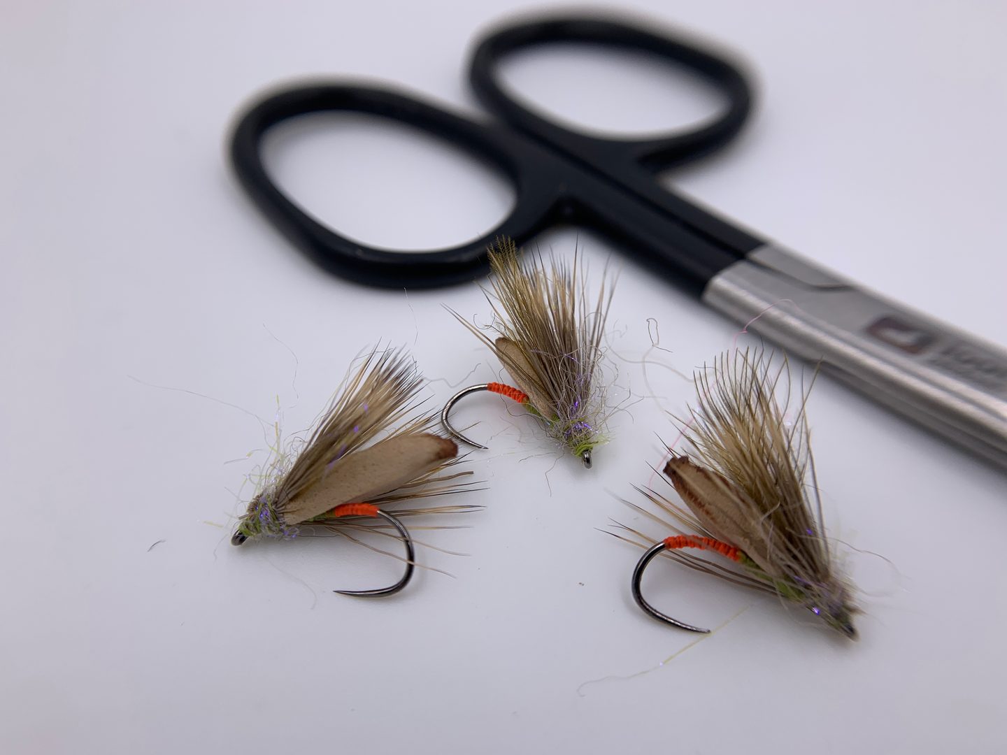 Hand-tied dry flies next to fly tying scissors
