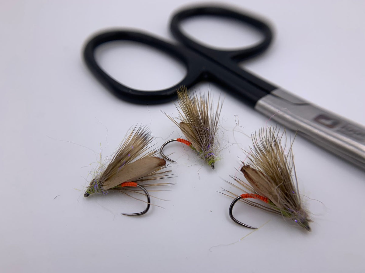 Hand-tied dry flies next to fly tying scissors