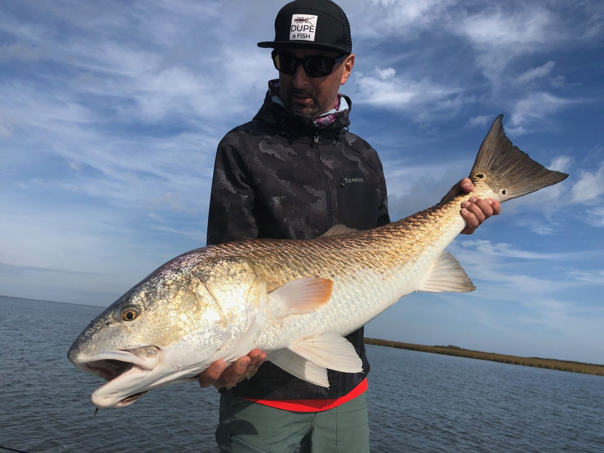 Angler holding a redfish caught on the fly in a Gulf Coast marsh