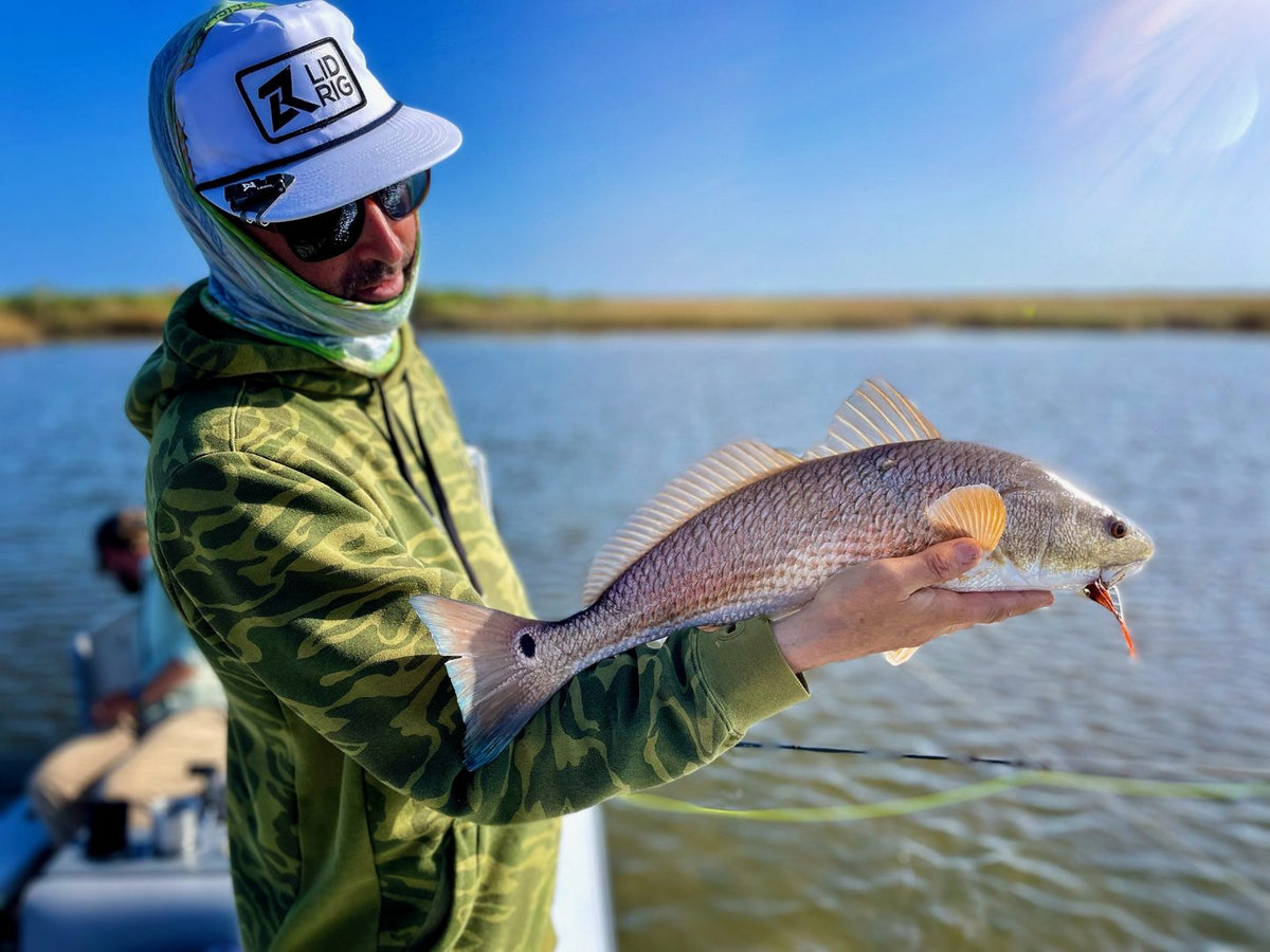 Angler holding a redfish caught on the fly in the Louisiana marsh