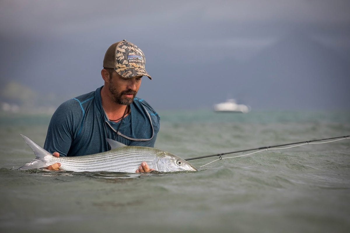 Angler wading a saltwater flat and holding a bonefish before release