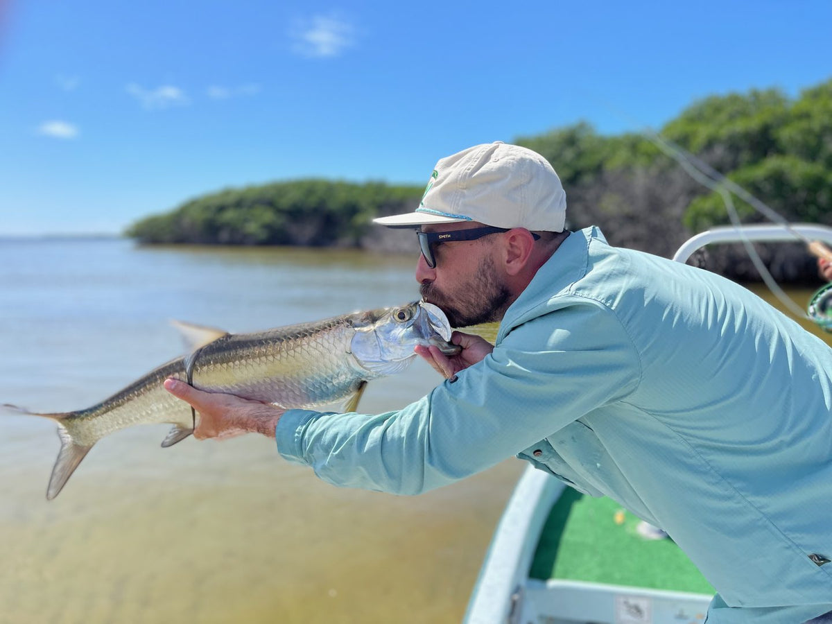 Angler releasing a tarpon over a shallow flat