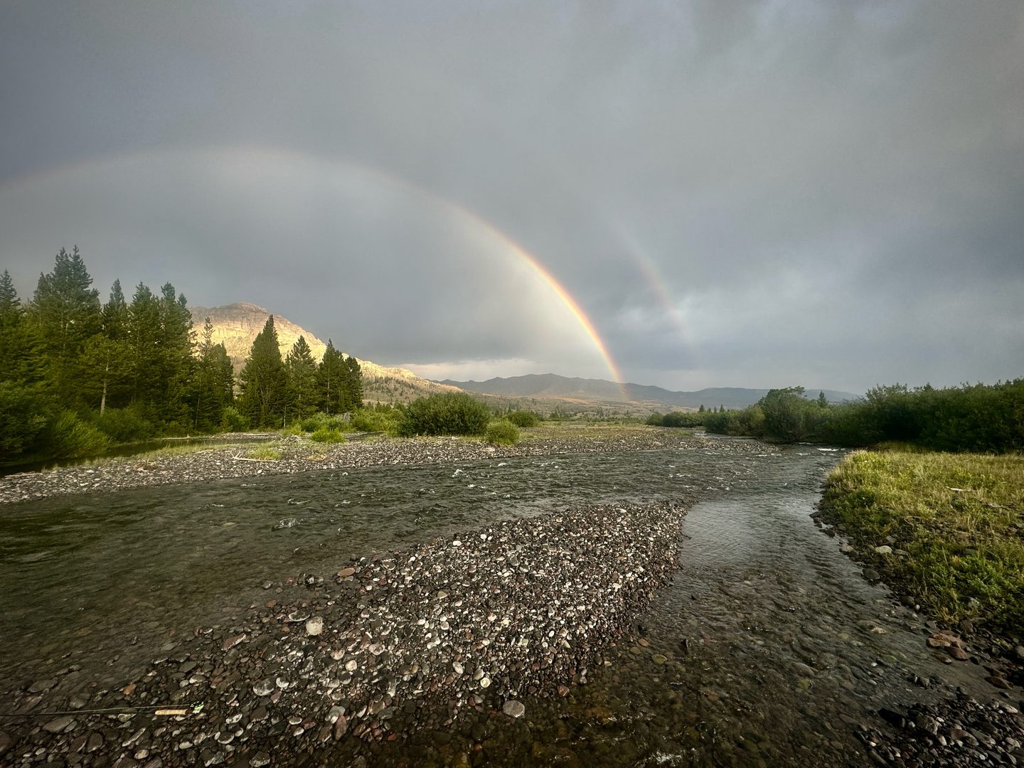 Freestone river running over a wide gravel bar under a rainbow