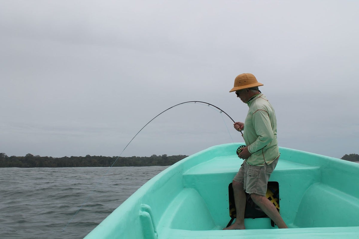 Angler with a bent rod fighting a fish from a panga