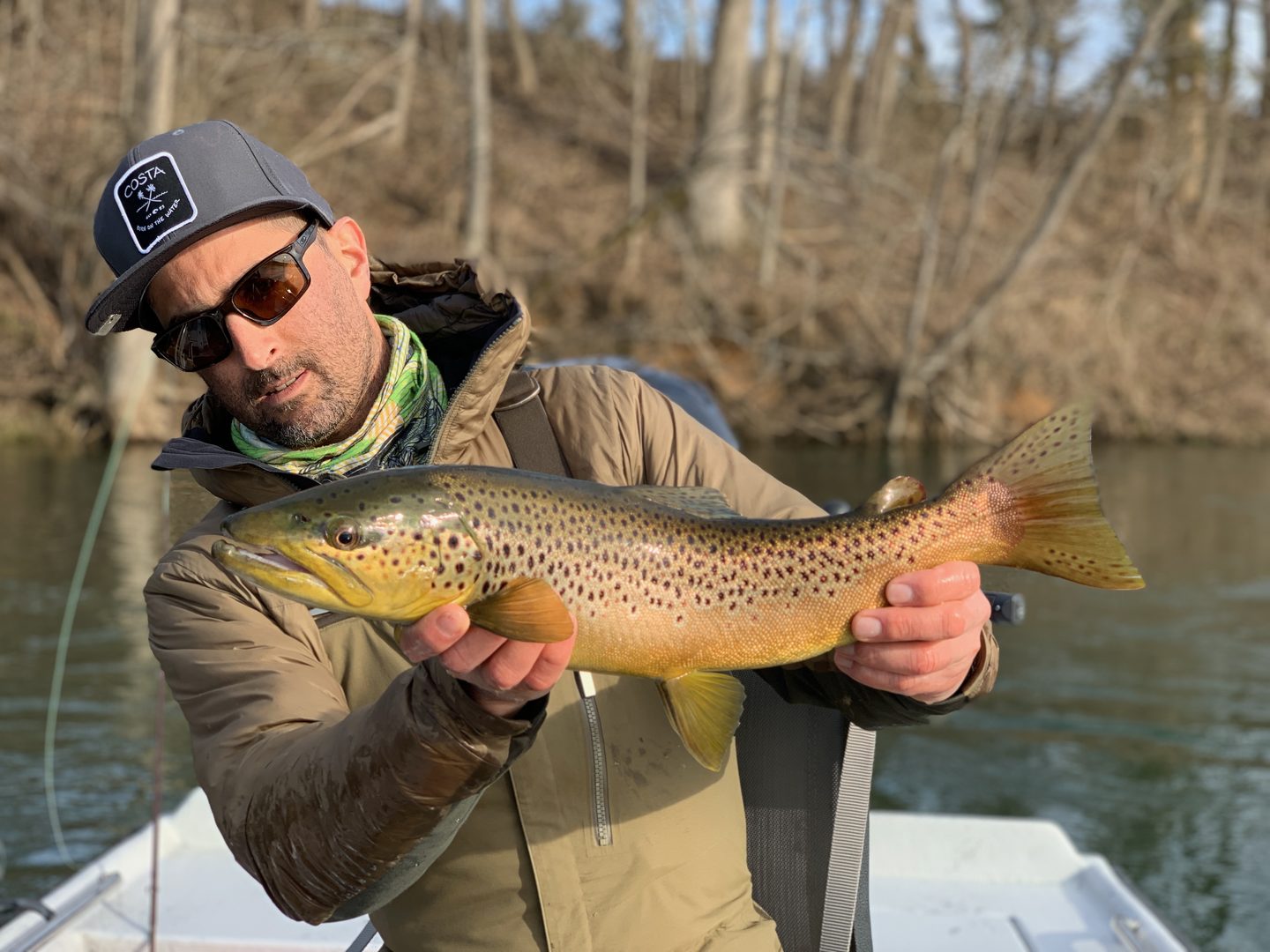 Angler holding a big brown trout on a river in fall