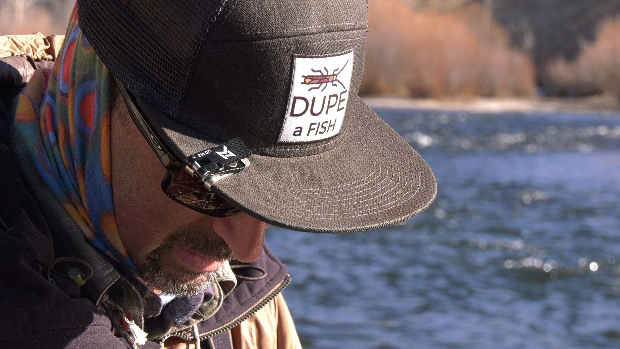 Angler looking down with an older Lid Rig magnetic nipper clipped to the brim of a Dupe a Fish cap