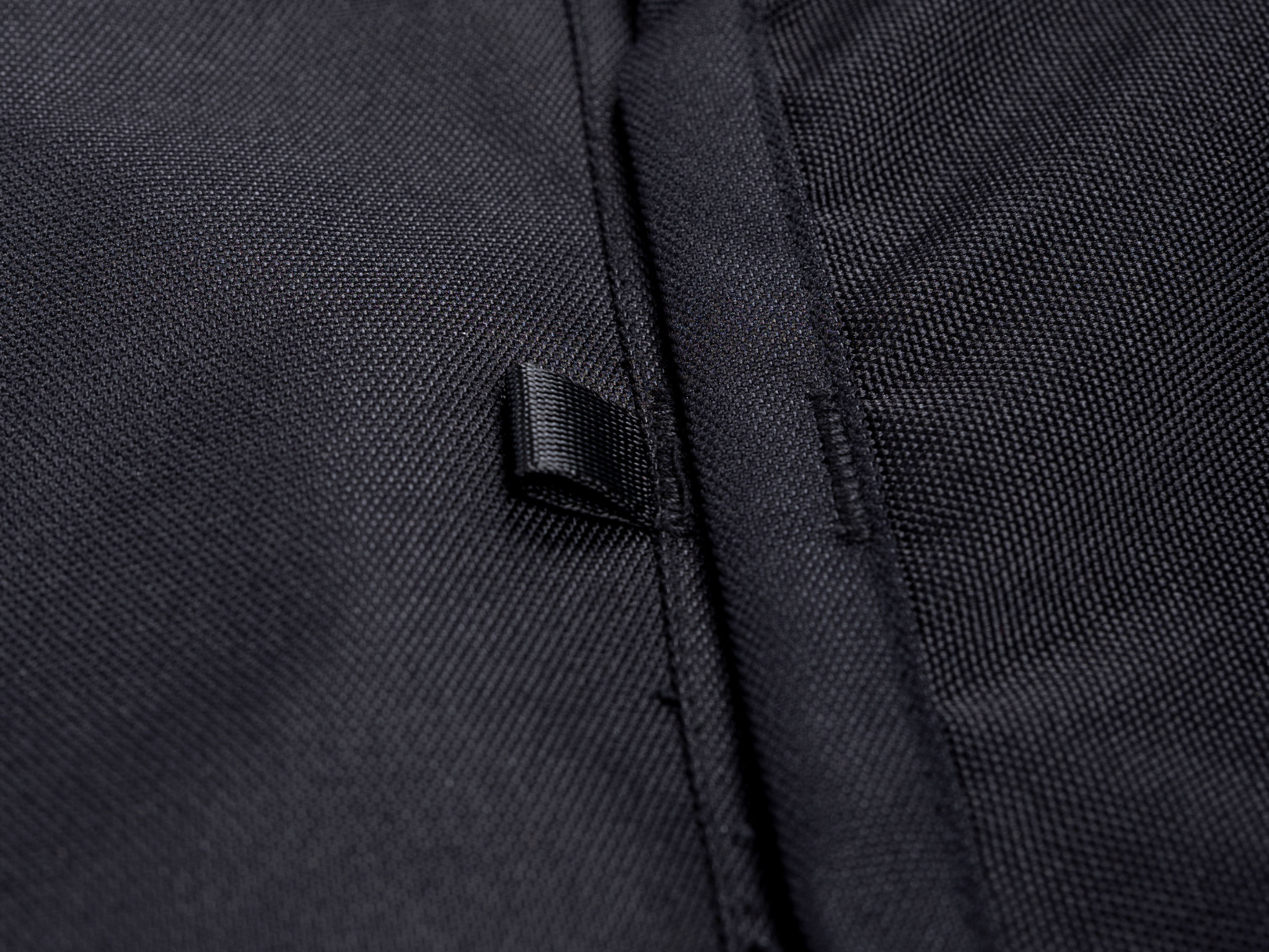 Black fabric storage panel edge with reinforced seam and woven loop detail