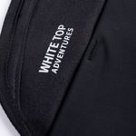 Black storage panel with label reading 'WHITE ADVENTURES' on woven fabric