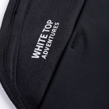 Black storage panel with label reading 'WHITE ADVENTURES' on woven fabric