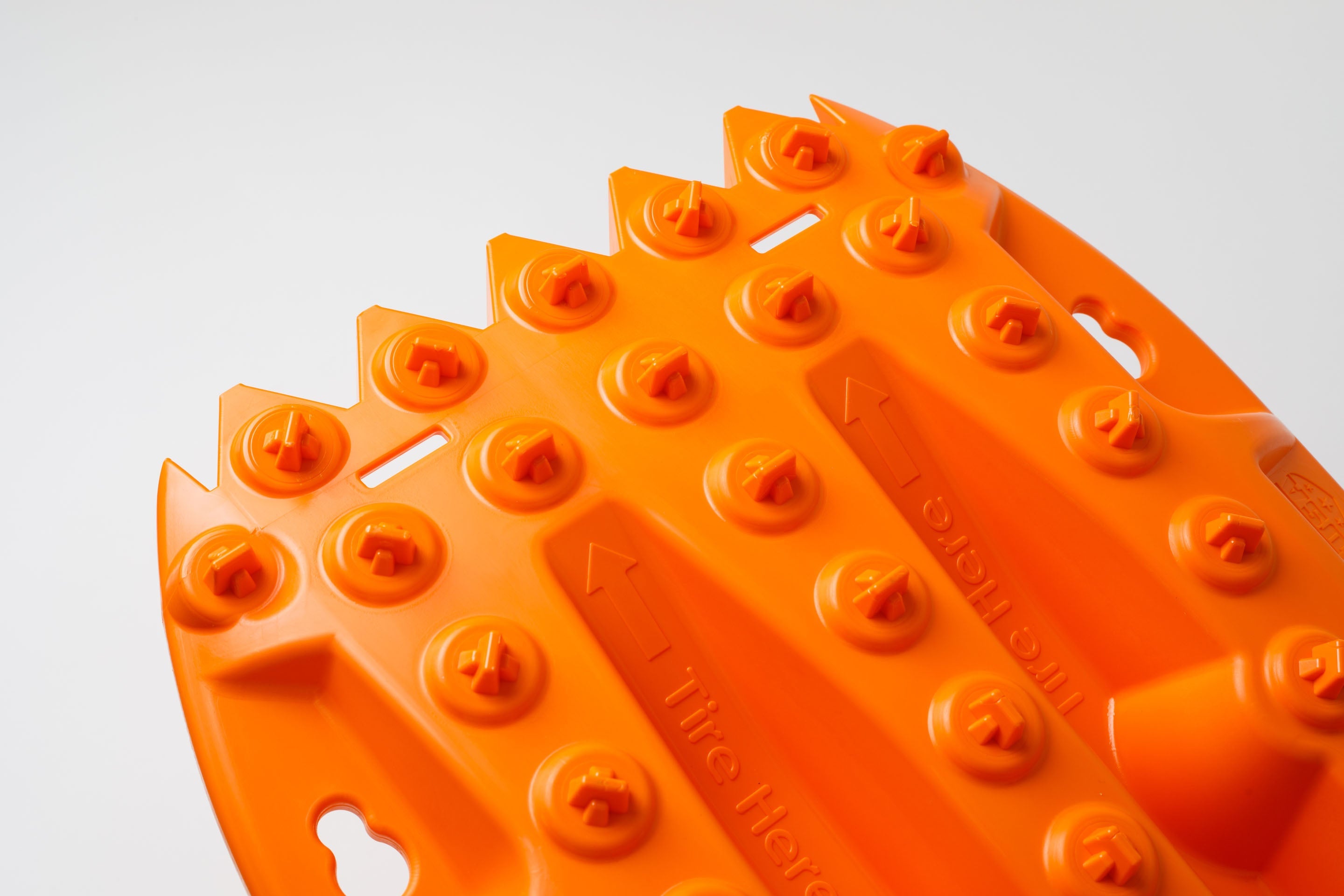Orange traction recovery board tread studs with embossed grip pattern