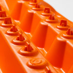 Orange traction mat close-up of triangular lugs and tread channels