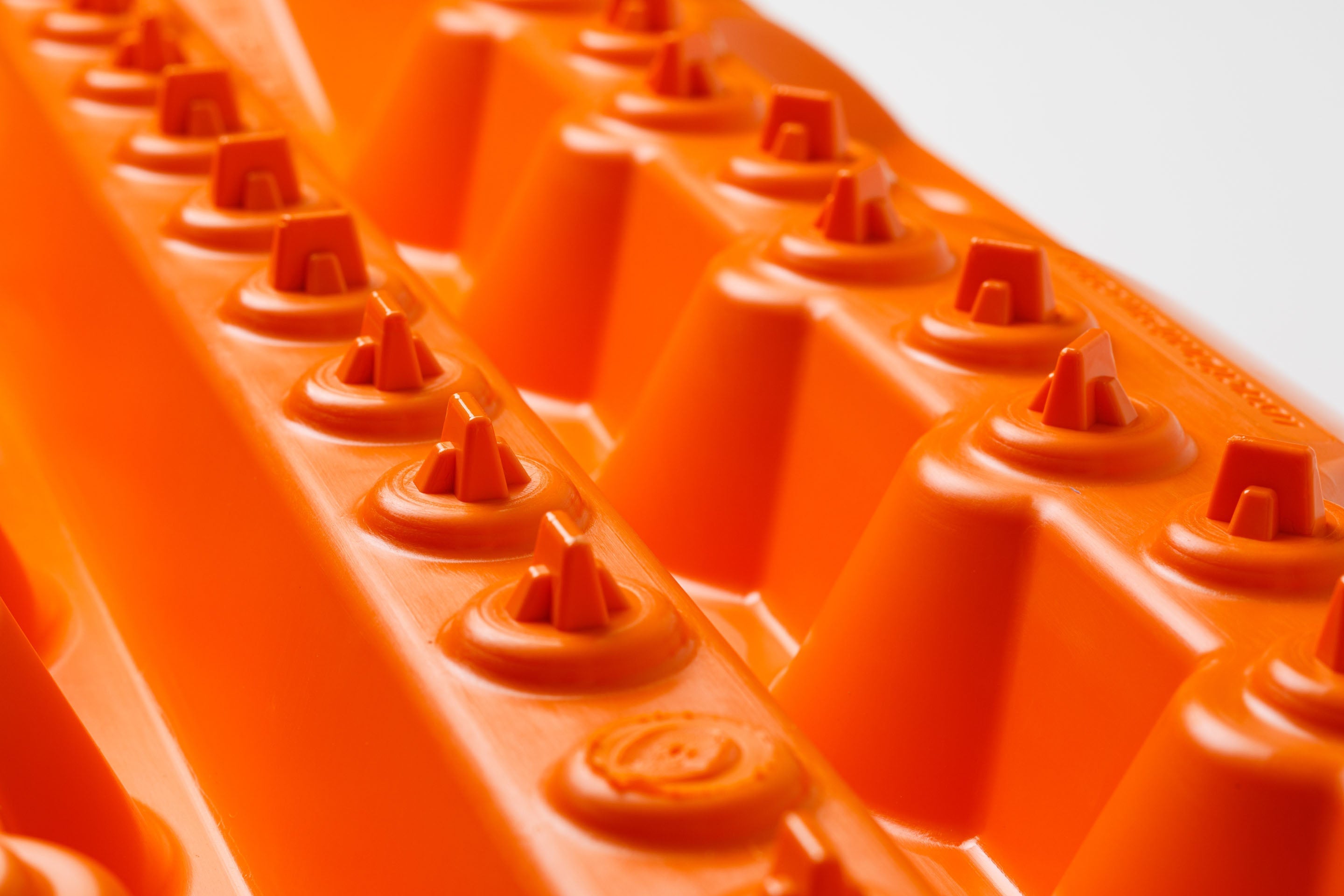 Orange traction mat close-up of triangular lugs and tread channels
