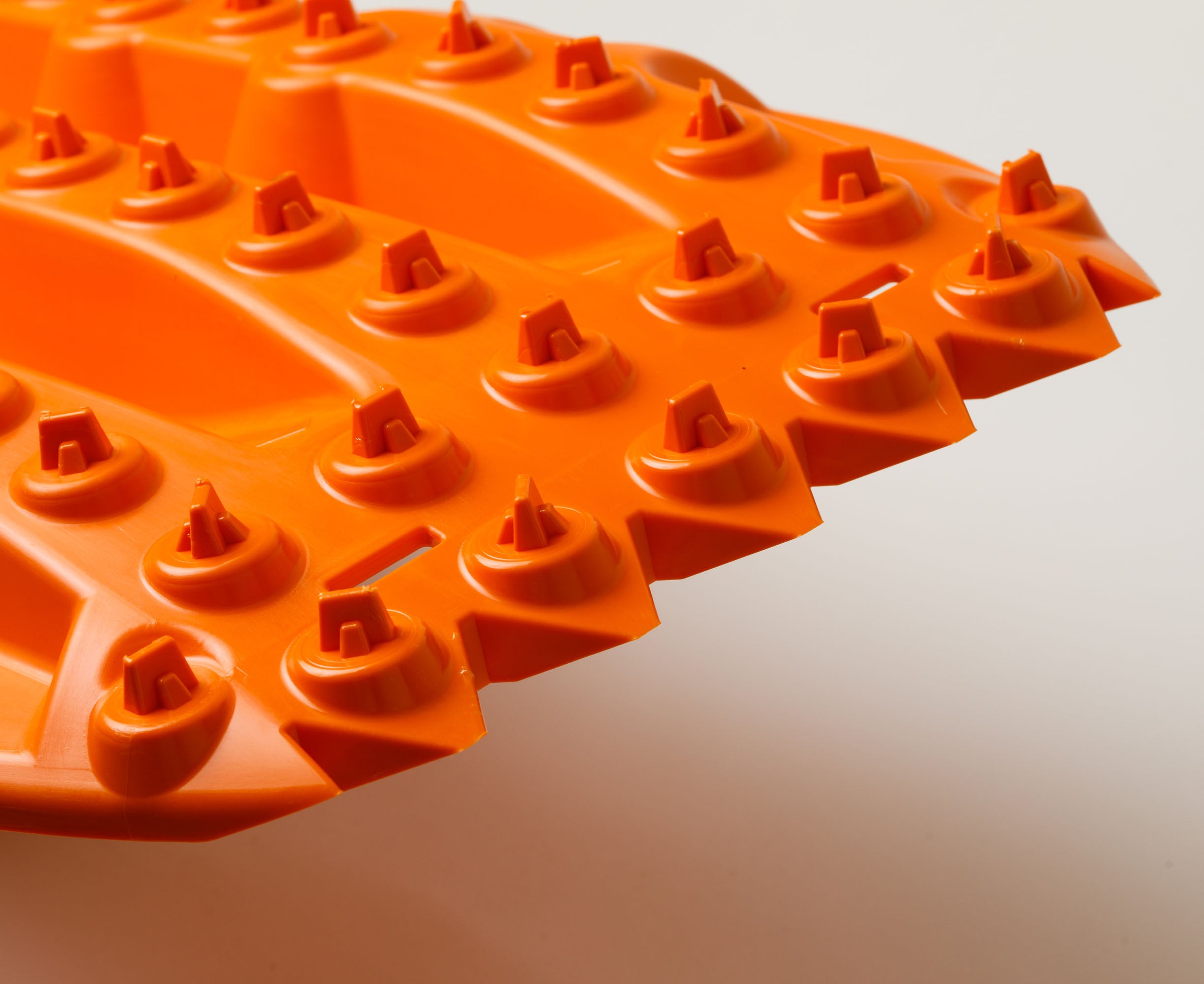 Orange traction board close-up of tread knobs and lugs
