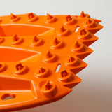 Off-road traction recovery board corner, orange spikes and raised traction knobs.
