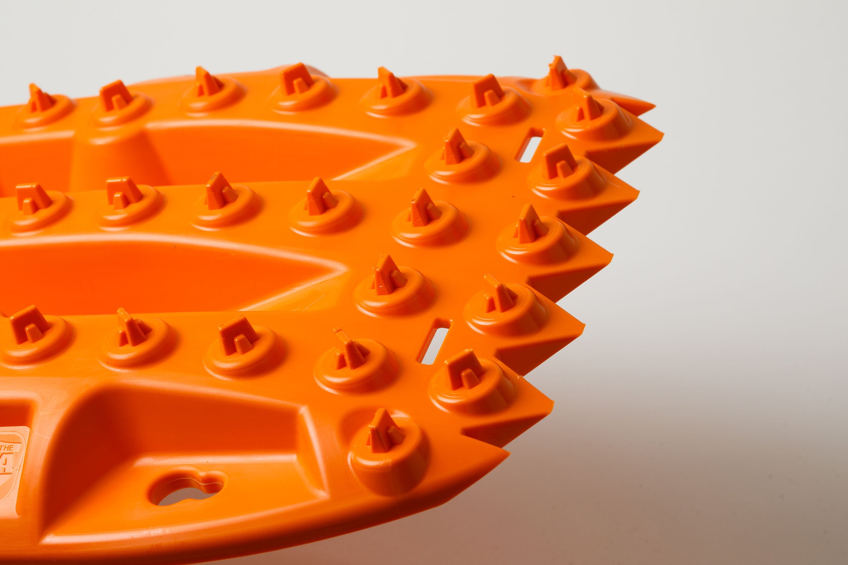 Off-road traction recovery board corner, orange spikes and raised traction knobs.