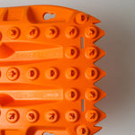 Orange traction mat tread end with toe slot and circular grip studs