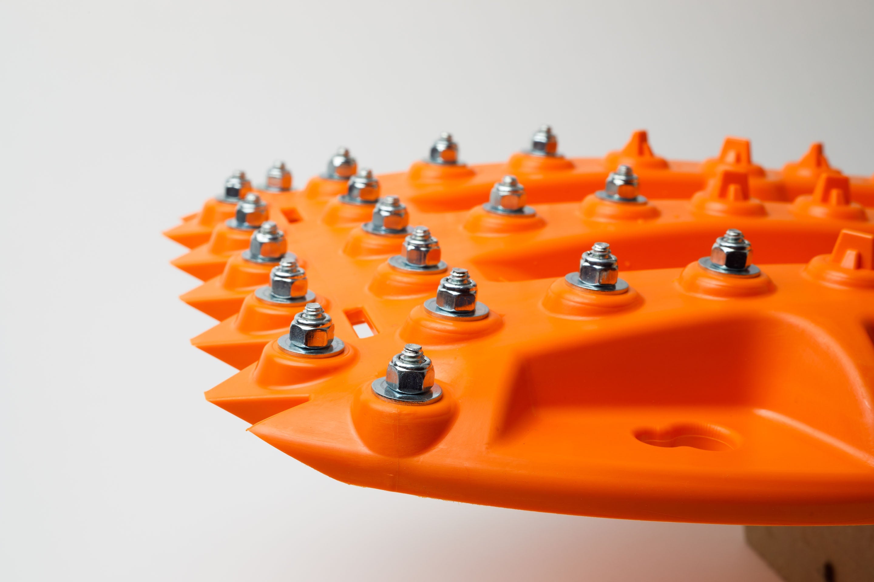Orange recovery traction mat with raised tread and metal stud bolts