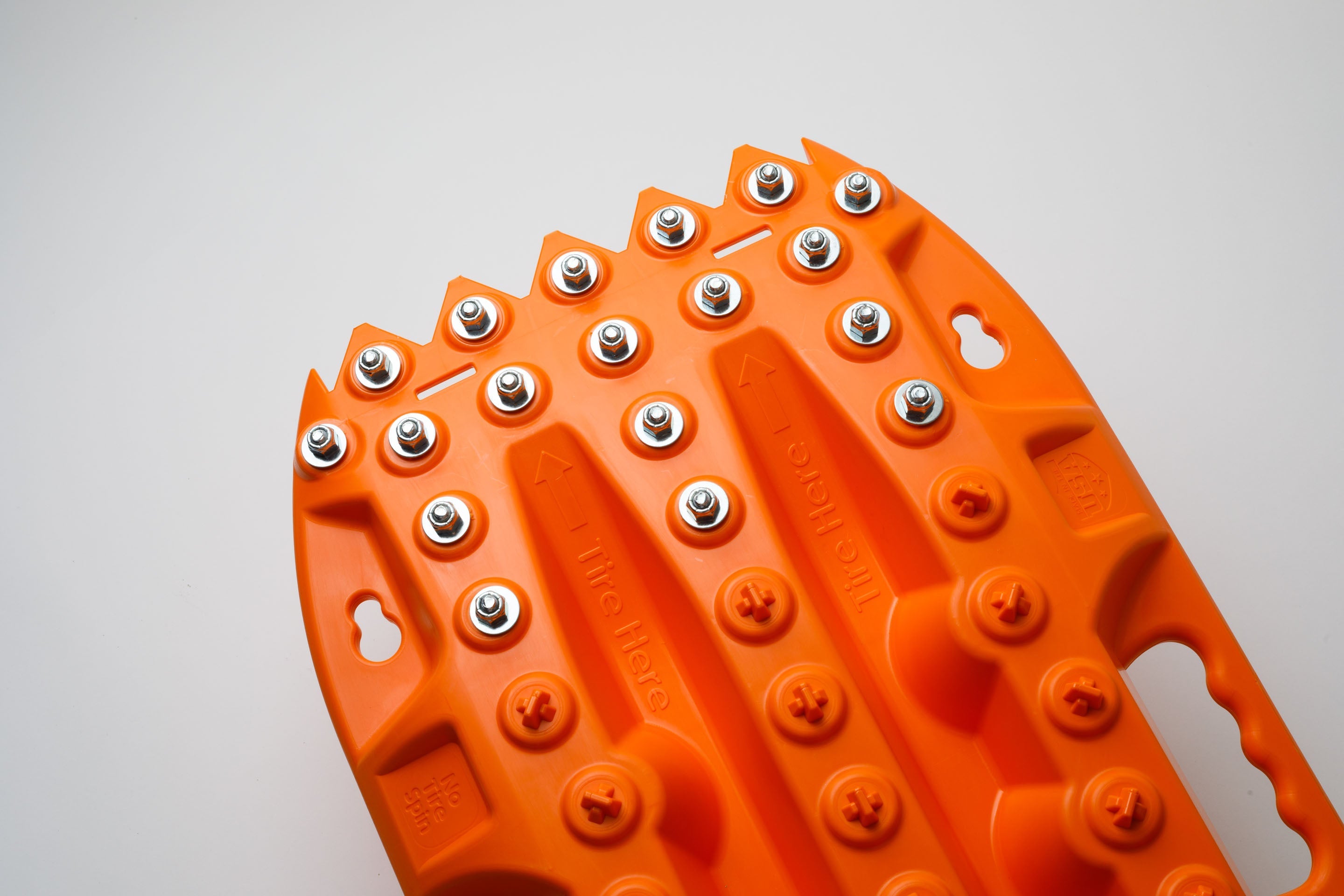 Orange metal-tooth traction board close-up with steel studs