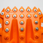Orange traction board top with rows of metal studs and embossed grip