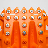 Orange traction board top with rows of metal studs and embossed grip