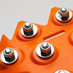 Orange traction board corner with five metal studs close-up