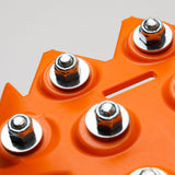 Orange traction board corner with five metal studs close-up