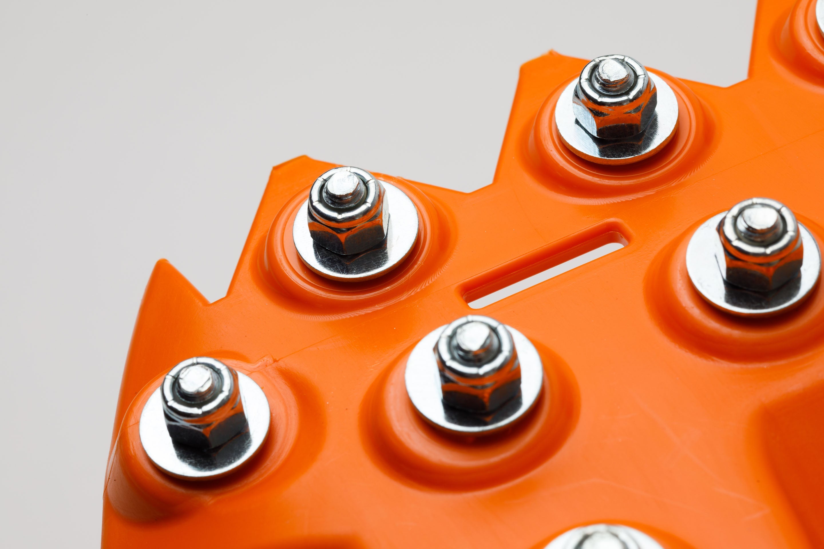Orange traction board corner with five metal studs close-up
