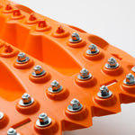 Orange traction board surface with multiple metal studs and grip ribs