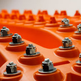 Orange traction recovery board surface with rows of metal tooth studs