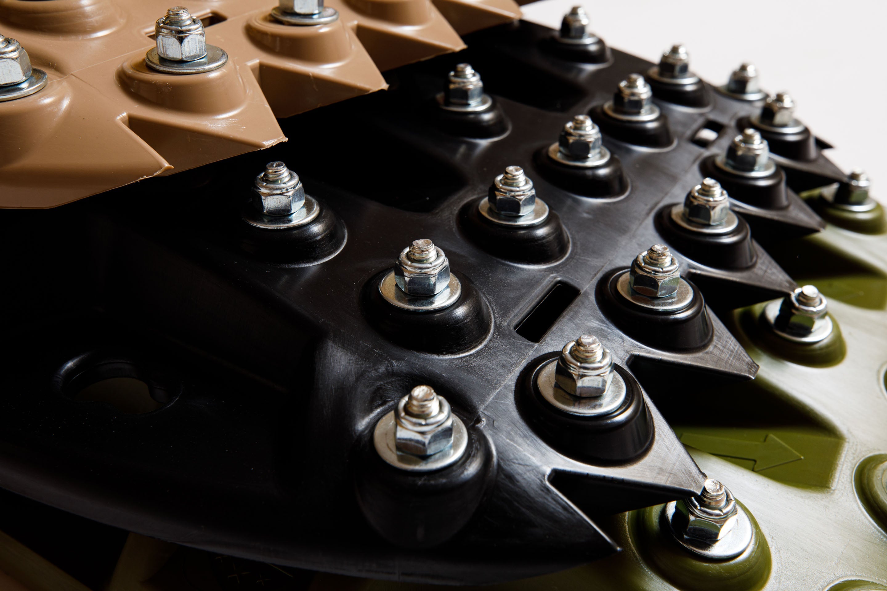Black recovery traction mat with metal tooth studs and bolt heads
