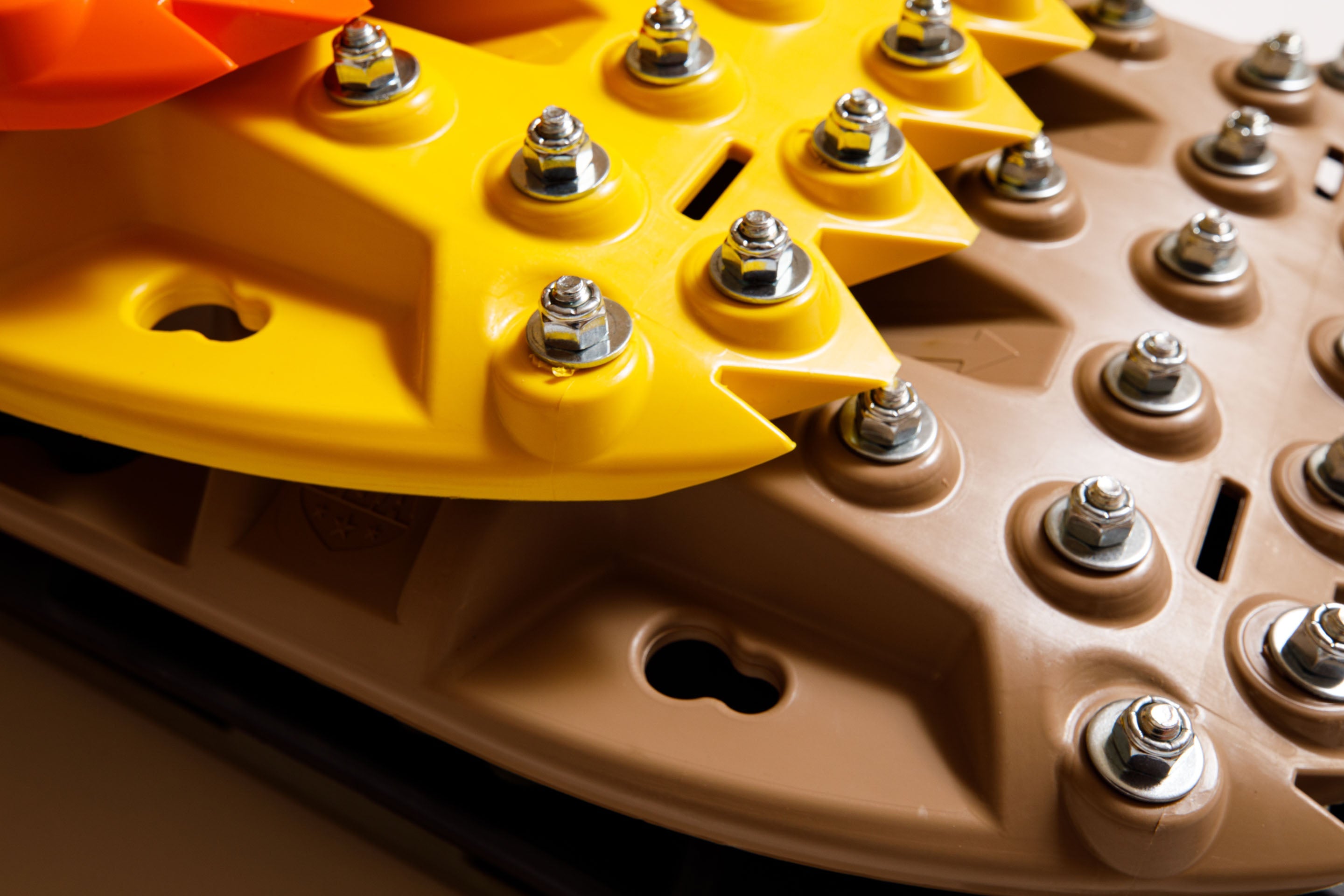 Tan recovery traction board with metal teeth studs on ridged surface