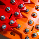 Close-up of red traction teeth with steel bolts on an orange-red board