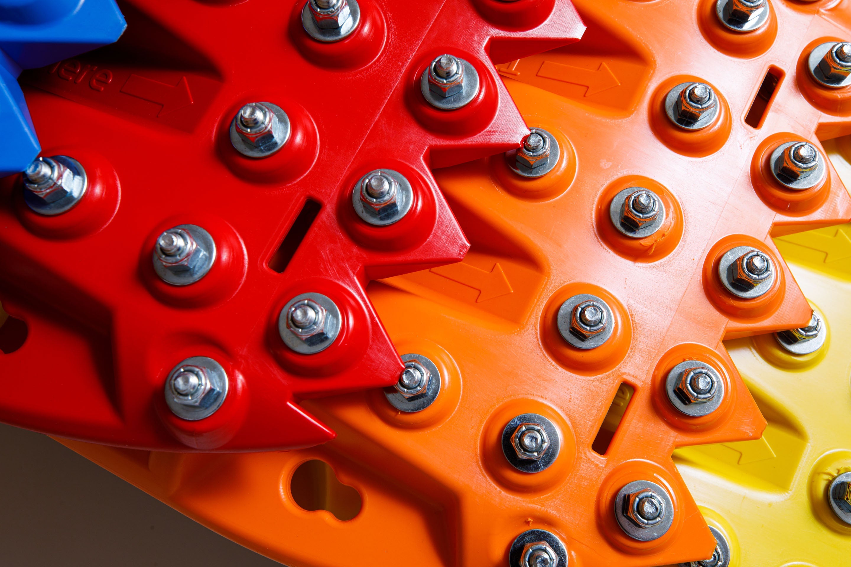 Close-up of red traction teeth with steel bolts on an orange-red board