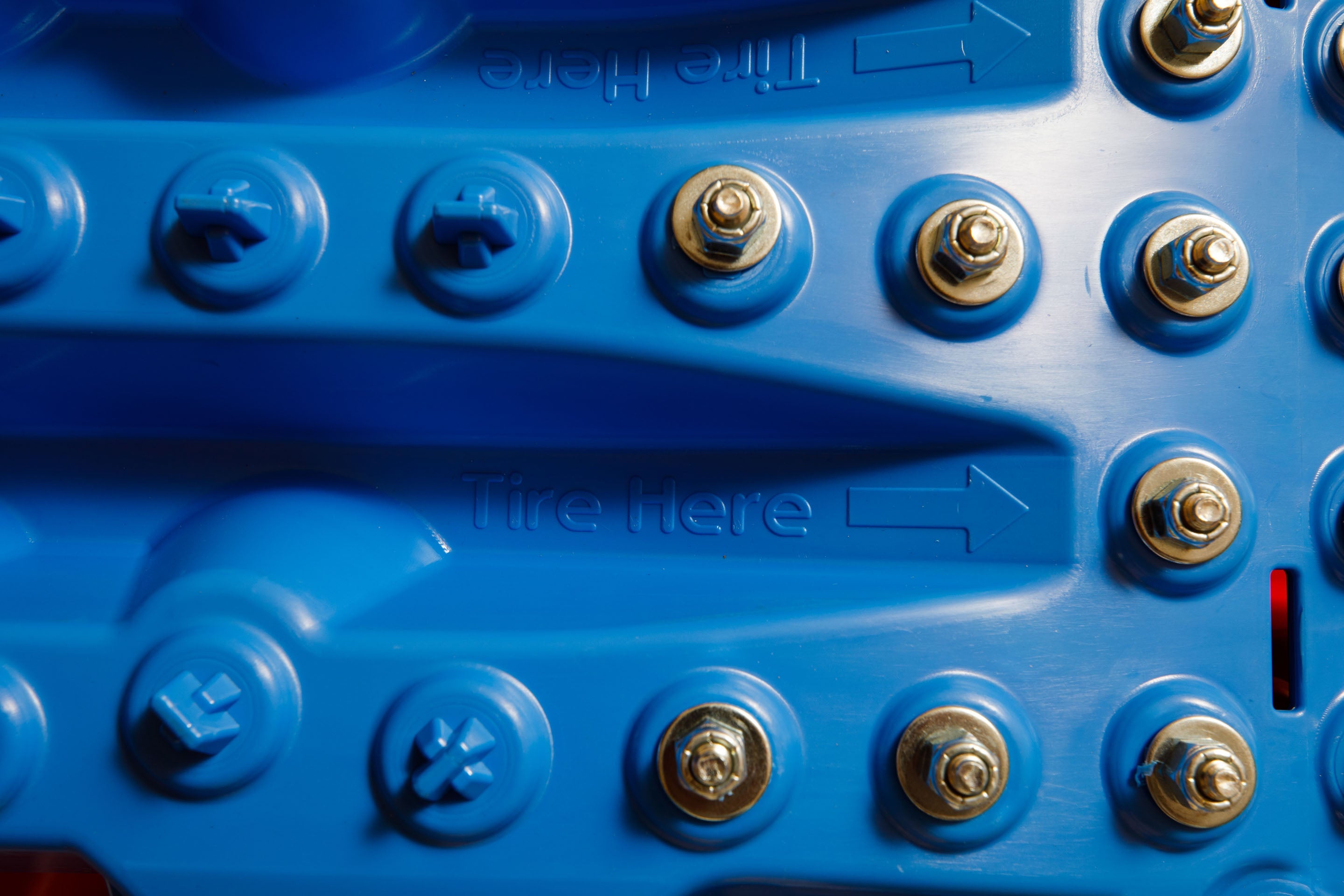 Close-up of blue traction mat with metal bolts on grip surface