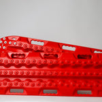 Red metal-tooth recovery traction board, side view with steel bolts