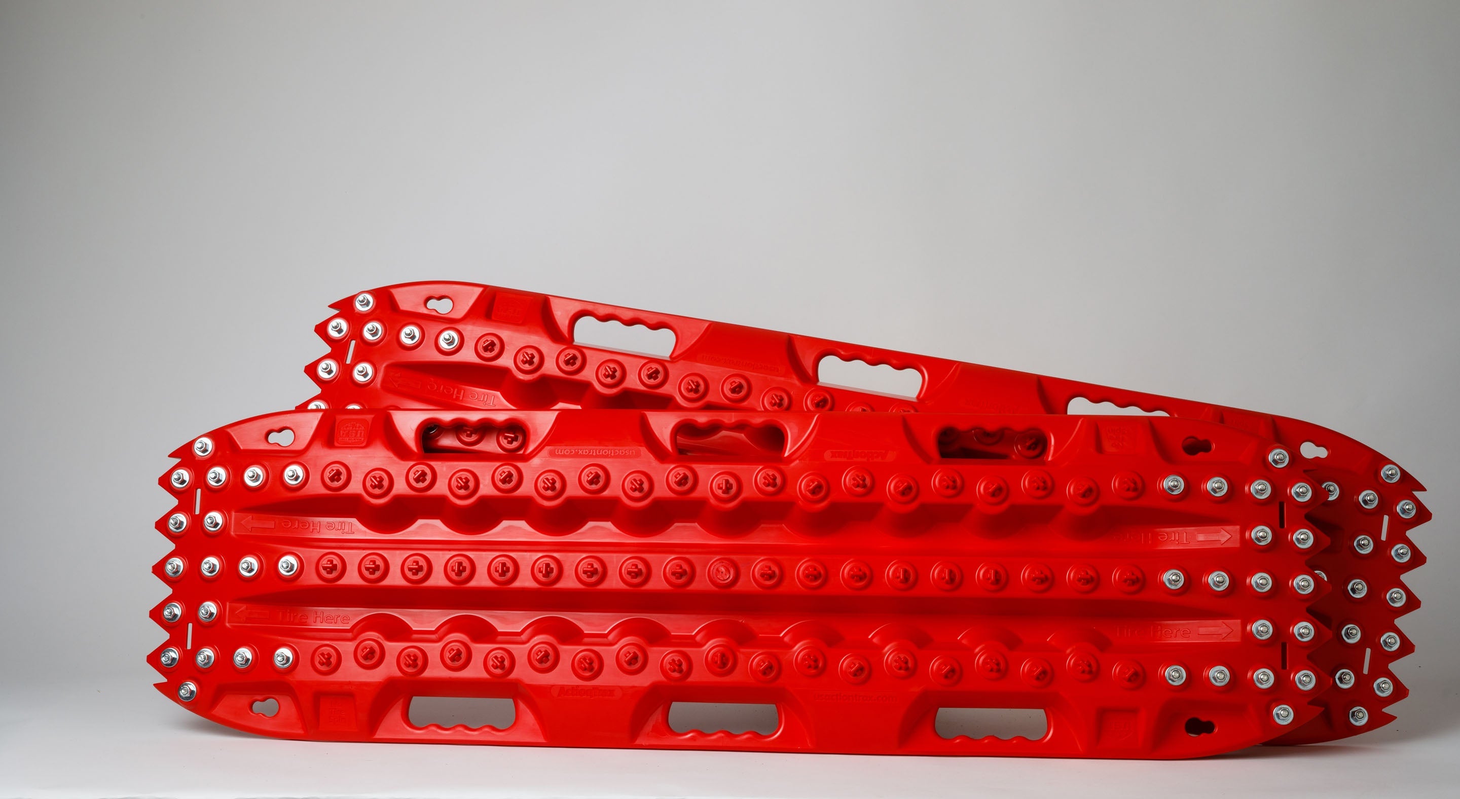 Red metal-tooth recovery traction board, side view with steel bolts