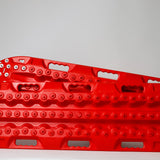 Red metal-tooth recovery traction board, side view with steel bolts