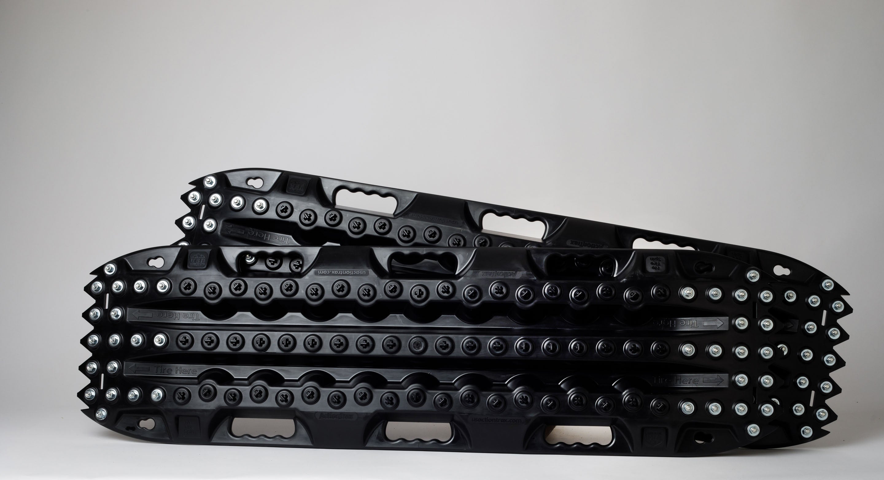 Pair of black traction recovery mats with metal teeth across the tread