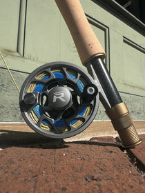 Dark gunmetal fishing reel with blue accents and large round spool