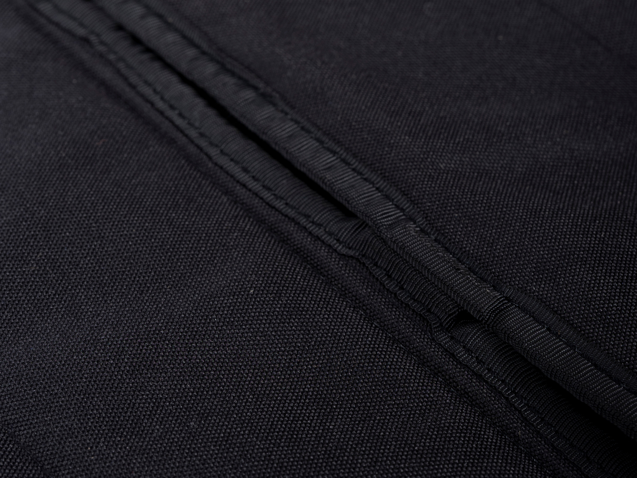 Black curtain fabric close-up showing textured weave and layered stitching