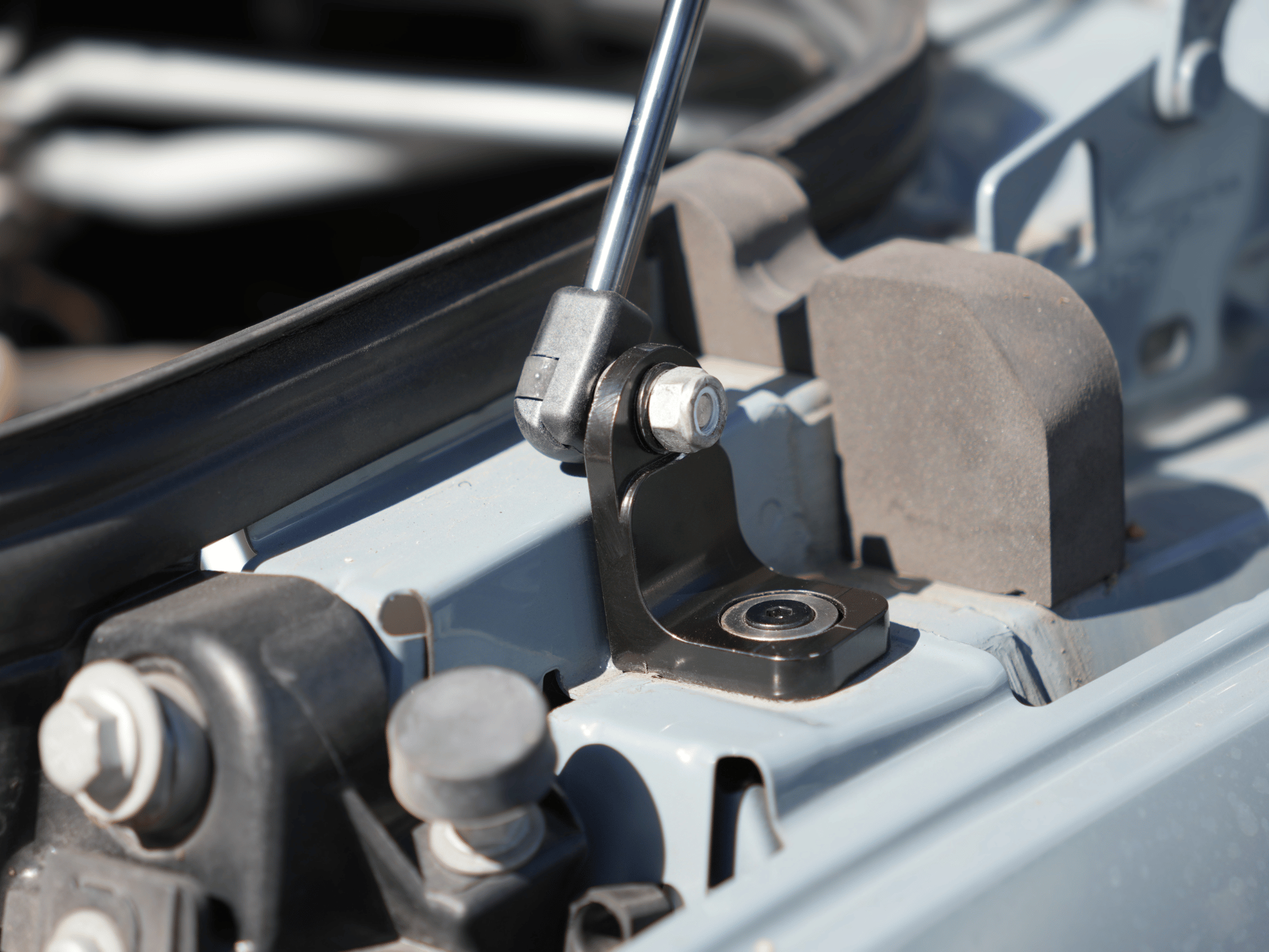 Installed hood strut on Sprinter van, showing bracket, pivot bolt, and bearing