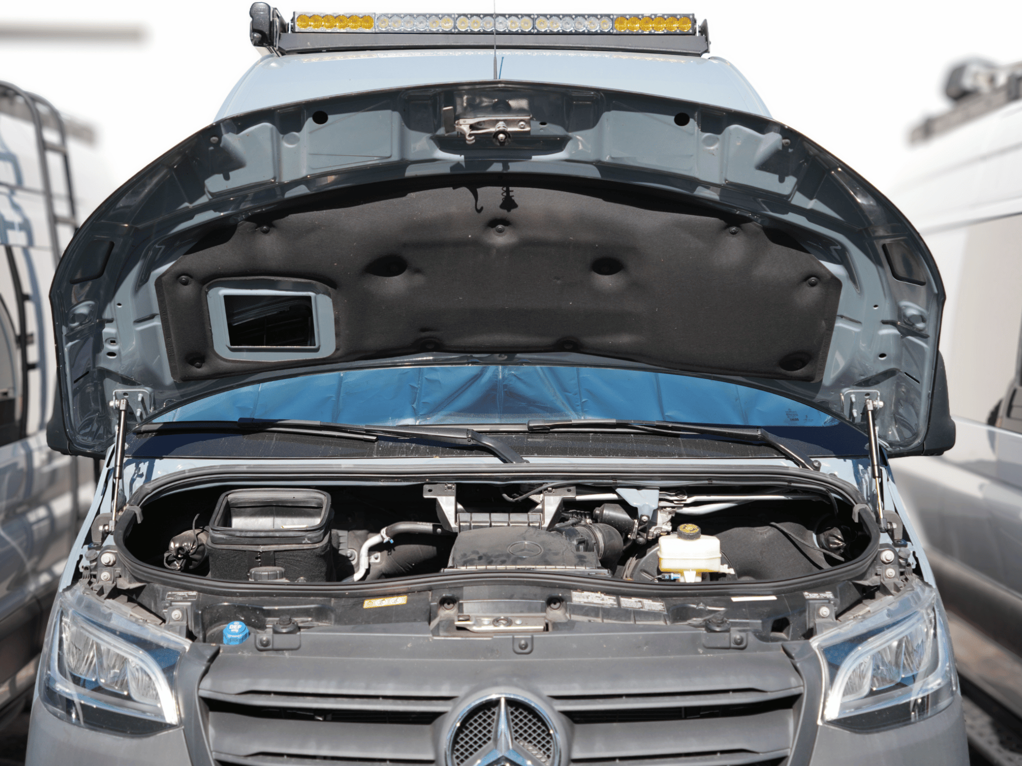 Open hood supported by hood struts in Sprinter van engine bay