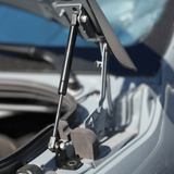 Hood strut assembly with pivot bracket holding the hood above engine bay