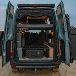 Wheel well box mini bed installed in van cargo area with open rear doors