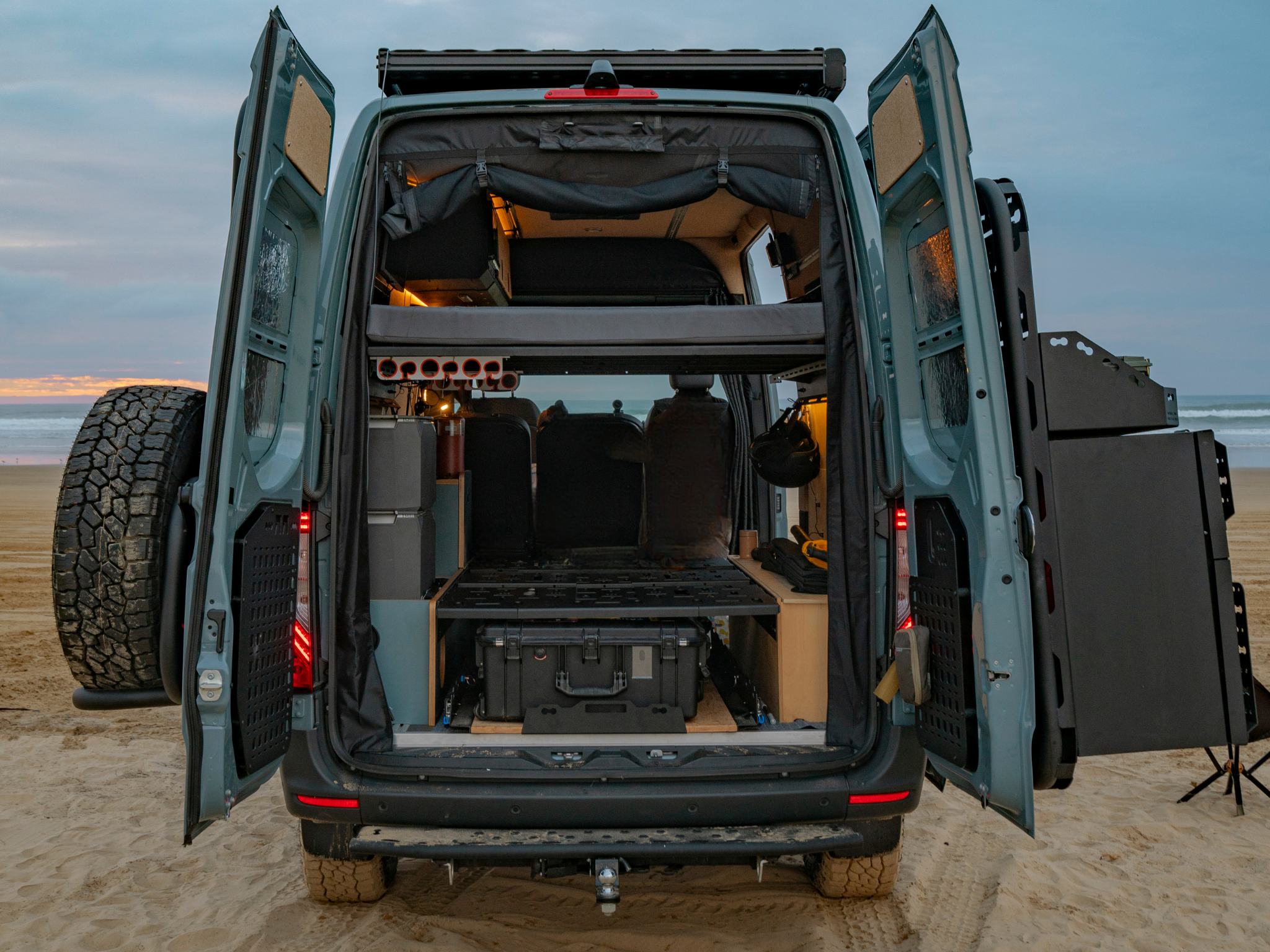 Wheel well box mini bed installed in van cargo area with open rear doors