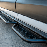 Installed black perforated side steps with anti-slip holes along the van