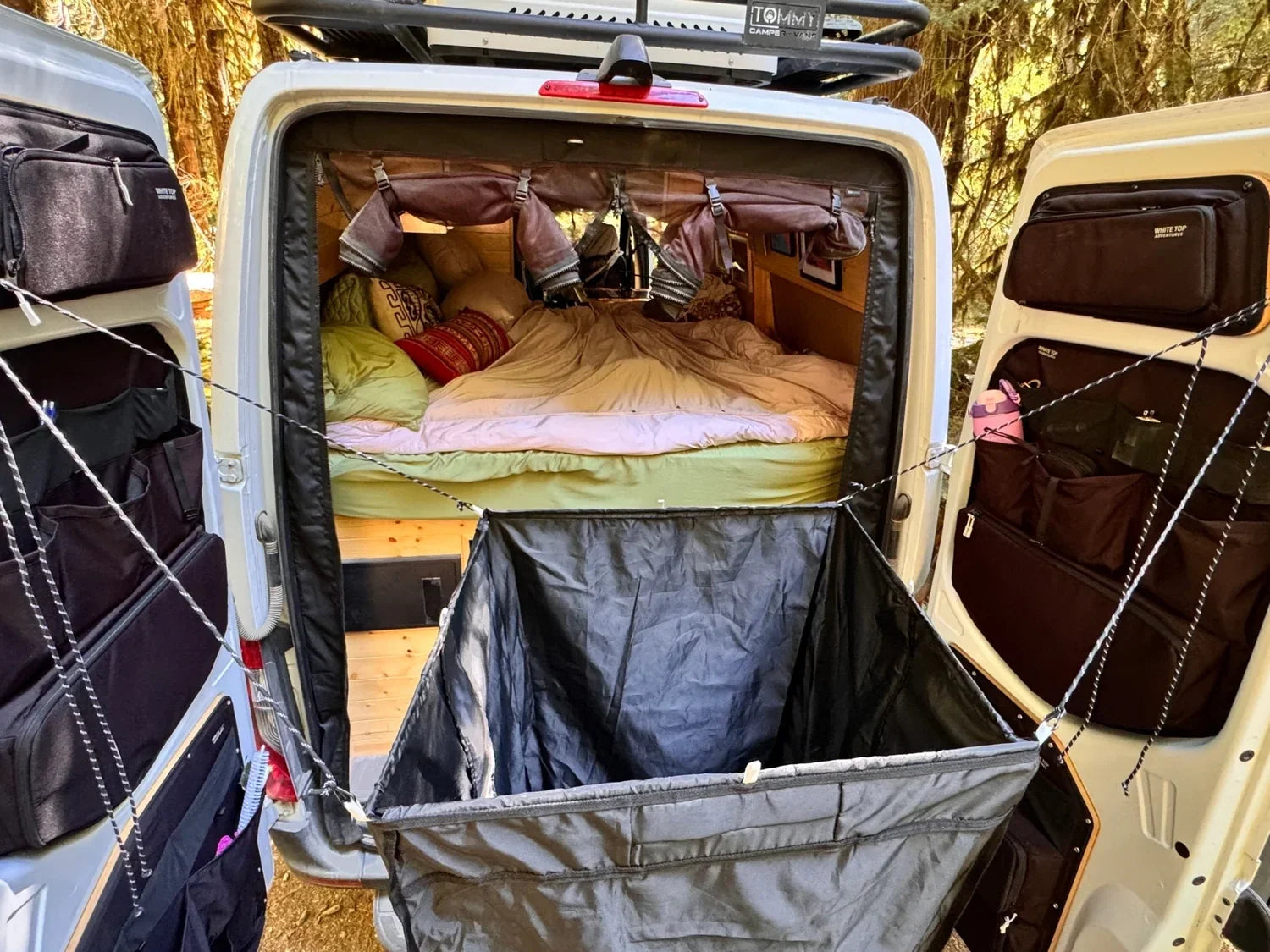 Opened shower kit bag with black liner and hanging compartments inside a van