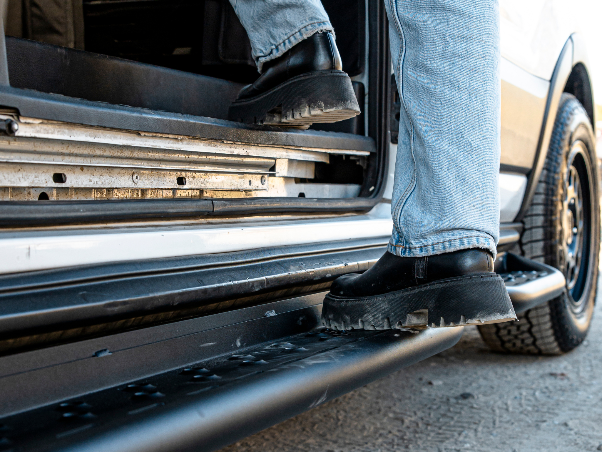 Under-steps view with black metal bars and perforations along the van