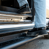 Under-steps view with black metal bars and perforations along the van