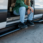 Black side steps under a Ford Transit with perforated tread for foot access